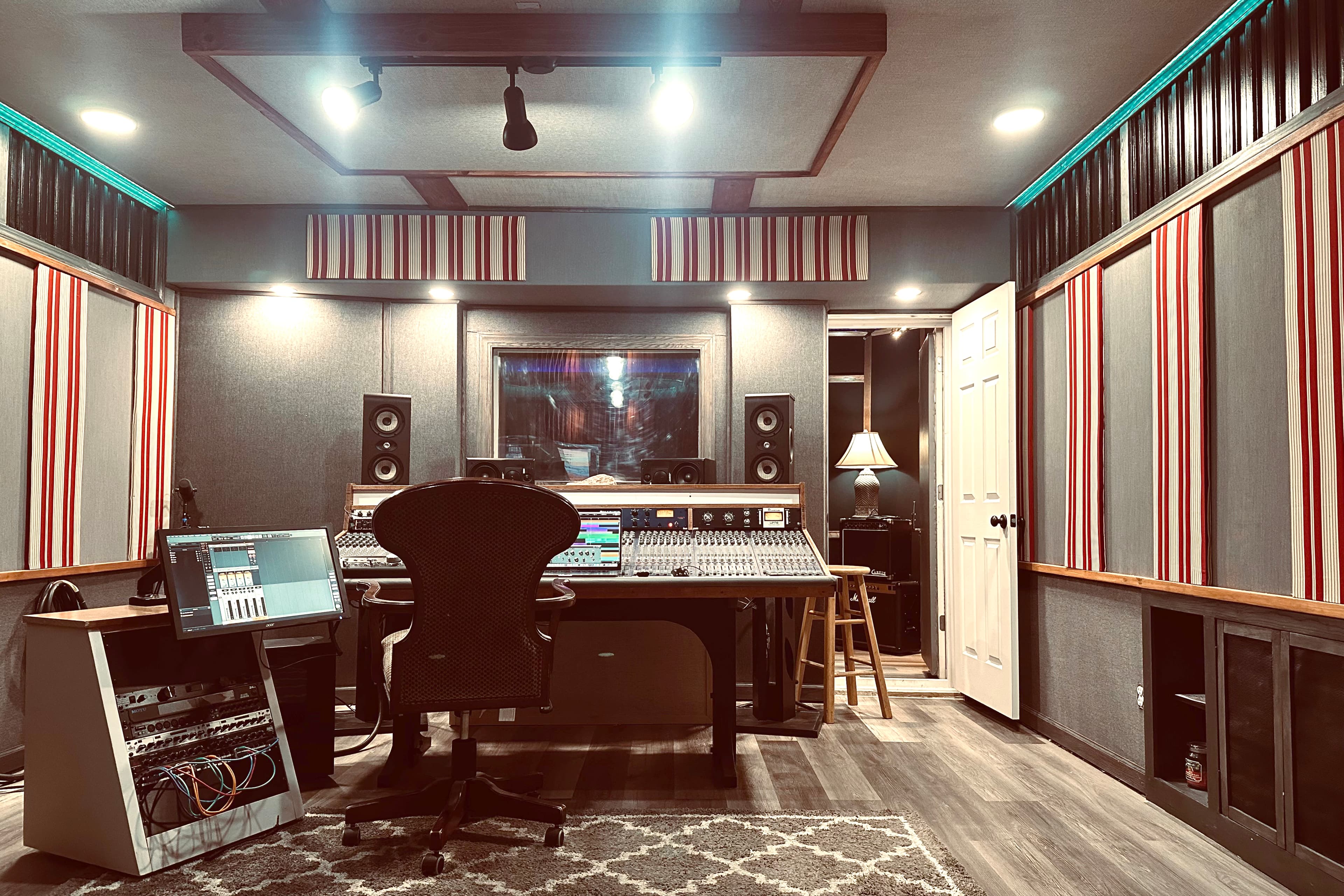 Wide view of the control room with mixing desk, monitors, racks, and acoustic treatment