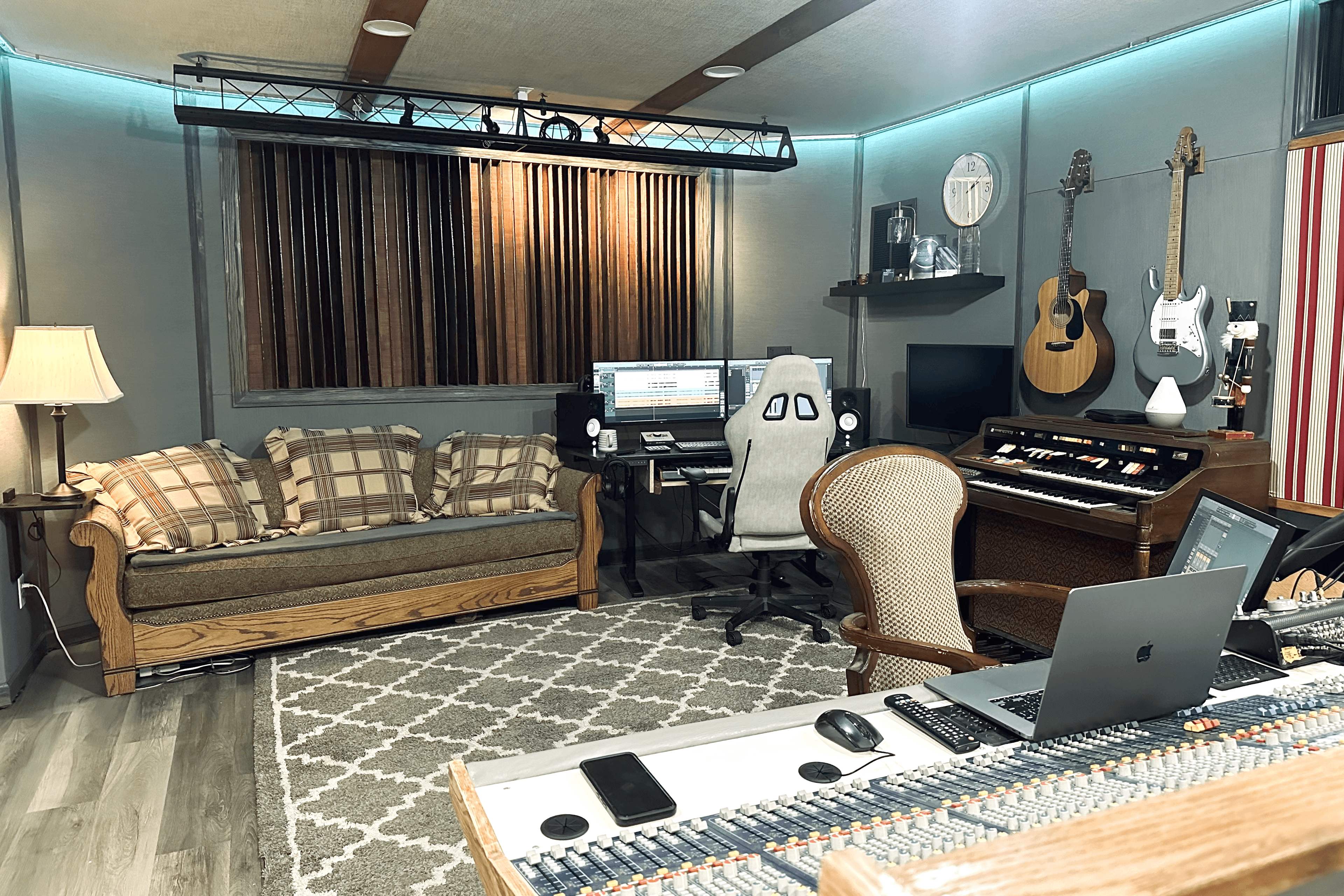 Studio live room and lounge with console, workstation, organ, and guitars