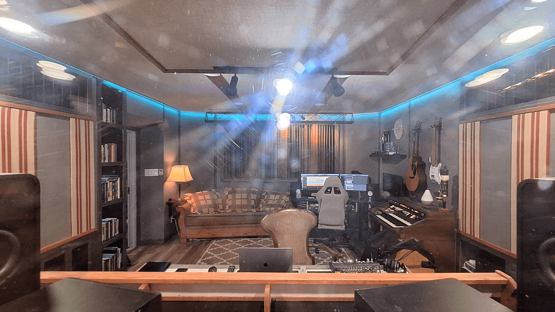 View of the control room from the vocal room, with console, monitors, and acoustic treatment in frame